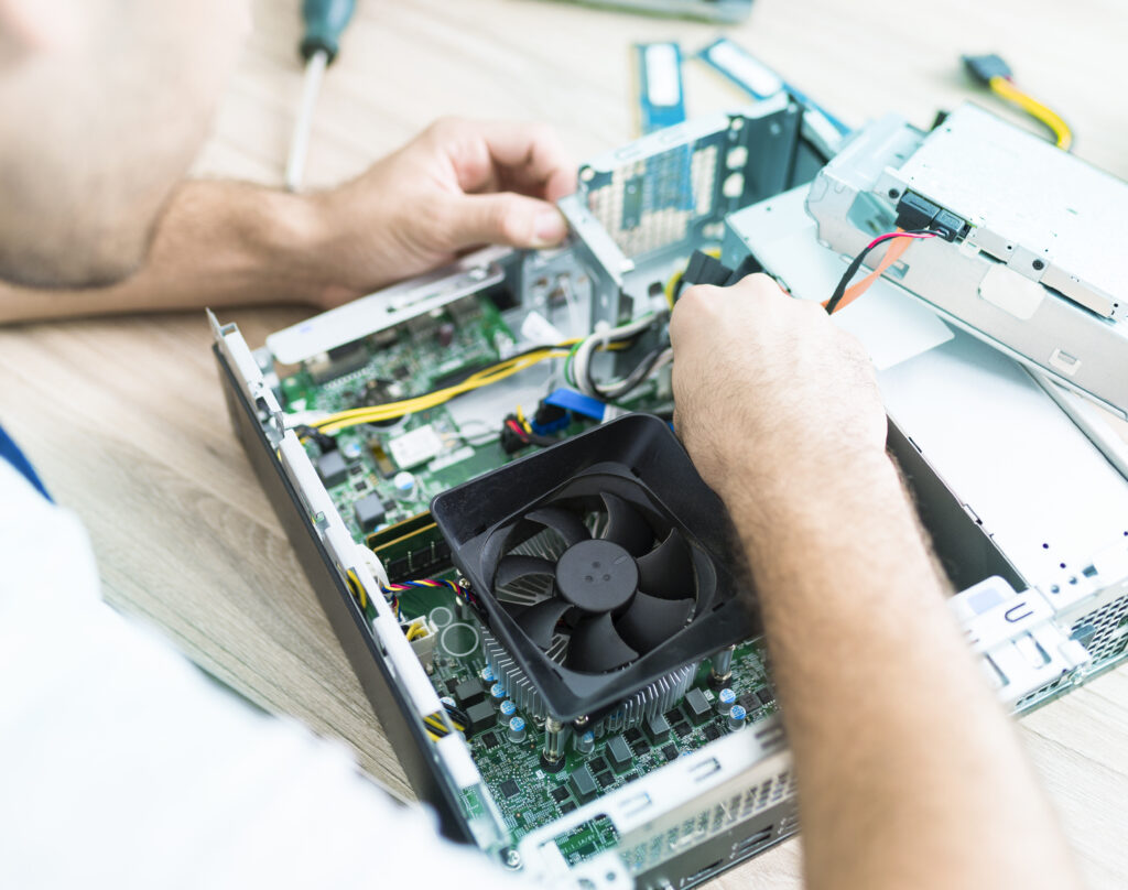 Man in repair workshop over open computer, working on parts such as processor cooler