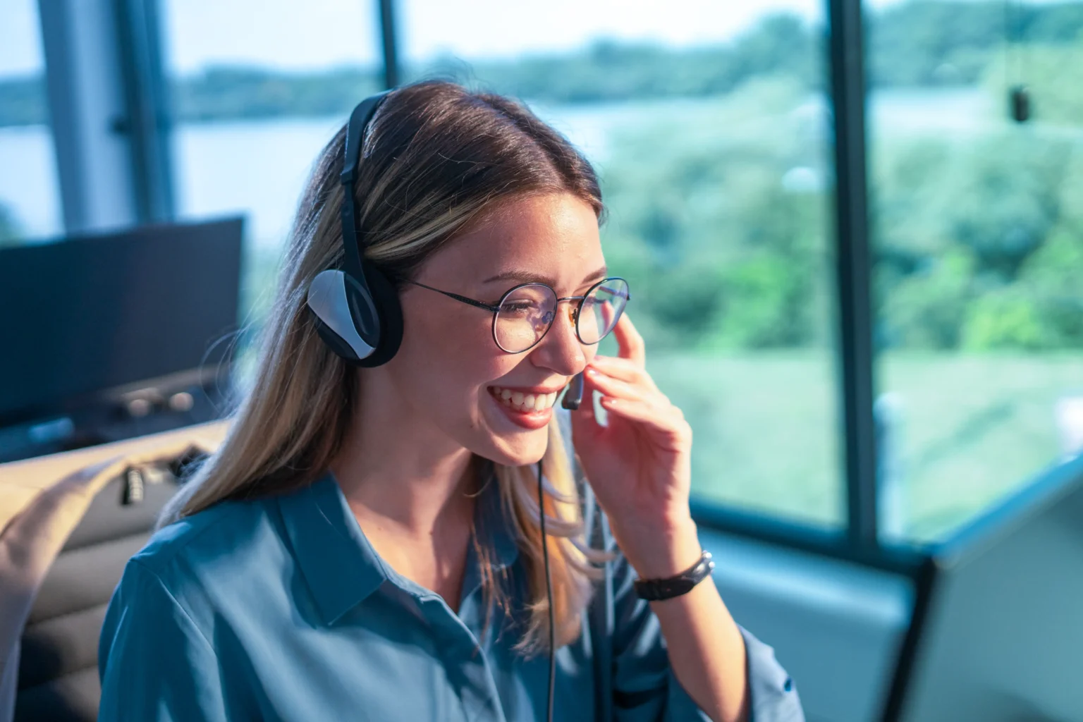 Office worker with a blue blouse communicates in a friendly manner via headset