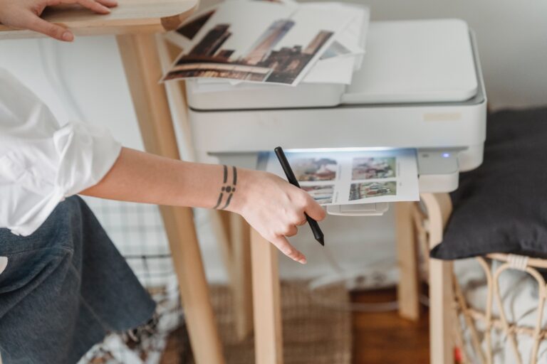 A woman pulling a sheet of paper out of a white printer